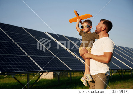 Aviator glasses and toy plane. Father with his little son are together near the solar panels Aviator glasses and toy plane. Father with his little son are together near the solar panels 133259173