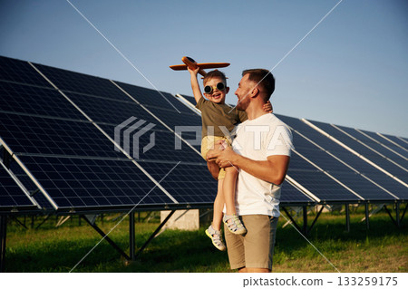 Aviator glasses and toy plane. Father with his little son are together near the solar panels Aviator glasses and toy plane. Father with his little son are together near the solar panels 133259175