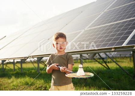 Holding the badminton racket. Little boy is with solar panels outdoors Holding the badminton racket. Little boy is with solar panels outdoors 133259228