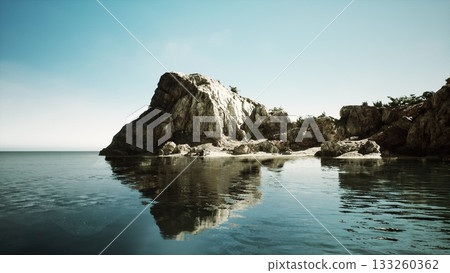 A rocky coastline emerges from calm waters, with serene reflections in the water. The clear blue sky enhances the tranquil beauty of this coastal scene, inviting peace and relaxation. A rocky coastline emerges from calm waters, with serene reflections in the water. The clear blue sky enhances the tranquil beauty of this coastal scene, inviting peace and relaxation. 133260362
