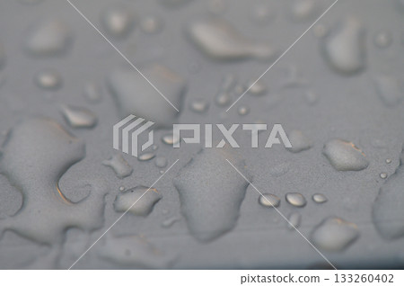 Water droplets glisten on a smooth surface reflecting soft light at dusk near a serene body of water Water droplets glisten on a smooth surface reflecting soft light at dusk near a serene body of water 133260402