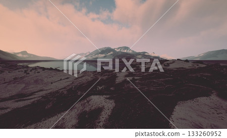 A tranquil landscape unfolds as the sun rises, illuminating a breathtaking view of mountains and a shimmering lake. The peaceful scene invites contemplation and appreciation of natures splendor. 133260952