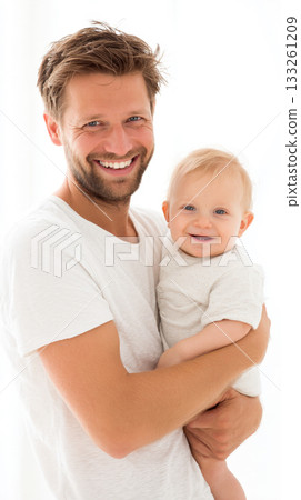 portrait of a bearded man, father in a white shirt, happily holding and looking at the camera with his smiling baby, infant. The image captures a sincere moment of paternal love and family joy. 133261209