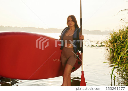 Plants growing on the side. Young woman is with the sup board on the lake Plants growing on the side. Young woman is with the sup board on the lake 133261277