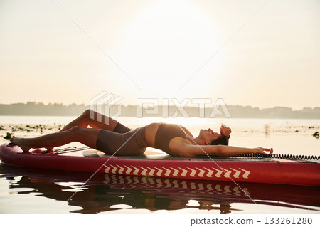 Relaxing, lying down. Young woman is with the sup board on the lake 133261280