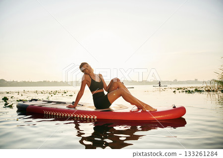 Taking a break, lying down on the sup board. Young woman is on the lake Taking a break, lying down on the sup board. Young woman is on the lake 133261284