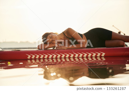 Lying down. Young woman is with the sup board on the lake 133261287