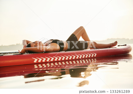 Lying down. Young woman is with the sup board on the lake Lying down. Young woman is with the sup board on the lake 133261289