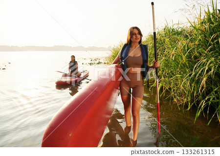 Walking to the shore. Women friends are on sup board on the lake together 133261315