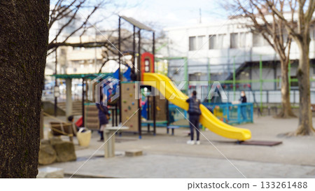 Image of a park where parents watch their children playing on a yellow slide Image of a park where parents watch their children playing on a yellow slide 133261488