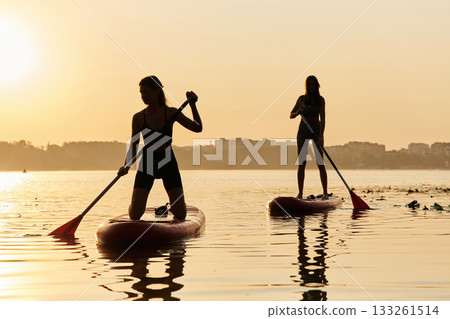 Summertime activities. Women friends are on sup board on the lake together 133261514