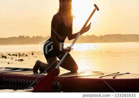 Darkened, illuminated by sunlight. Young woman is with the sup board on the lake Darkened, illuminated by sunlight. Young woman is with the sup board on the lake 133261633