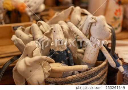 Handmade fabric rabbit toys arranged in a cozy display. Soft textile materials, warm tones and charming handcrafted details create a rustic decorative scene Handmade fabric rabbit toys arranged in a cozy display. Soft textile materials, warm tones and charming handcrafted details create a rustic decorative scene 133261649