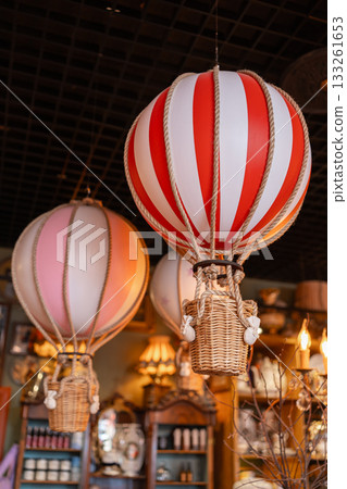 Decorative hot air balloons in a beautifully arranged interior. Soft lights, warm colors and elegant ornaments create a charming festive space with a travel-inspired theme Decorative hot air balloons in a beautifully arranged interior. Soft lights, warm colors and elegant ornaments create a charming festive space with a travel-inspired theme 133261653