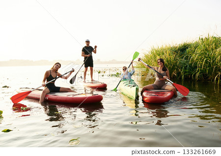 On the lake. Friends are together on sup boards On the lake. Friends are together on sup boards 133261669