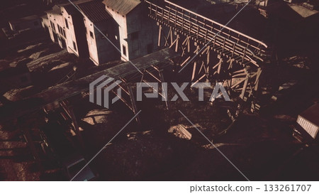 A deserted industrial area basks in the warm glow of sunset. Weathered structures and rusting beams create an atmosphere of forgotten memories, inviting exploration and imagination. A deserted industrial area basks in the warm glow of sunset. Weathered structures and rusting beams create an atmosphere of forgotten memories, inviting exploration and imagination. 133261707