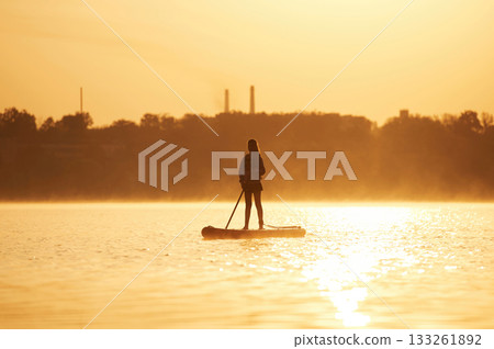 Illuminated by sunlight. Girl kid is on the sup board, on the lake Illuminated by sunlight. Girl kid is on the sup board, on the lake 133261892