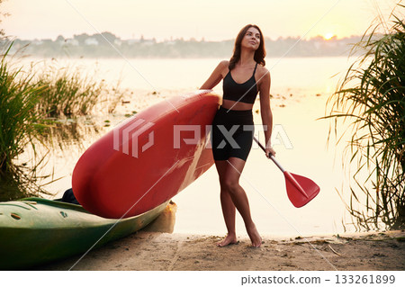 Posing, standing on the shore. Young woman is with the sup board on the lake Posing, standing on the shore. Young woman is with the sup board on the lake 133261899