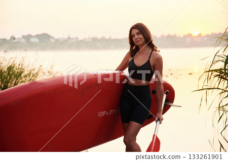Posing, standing on the shore. Young woman is with the sup board on the lake Posing, standing on the shore. Young woman is with the sup board on the lake 133261901
