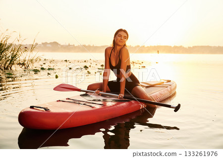 Positive, joyful facial expression. Young woman is with the sup board on the lake 133261976