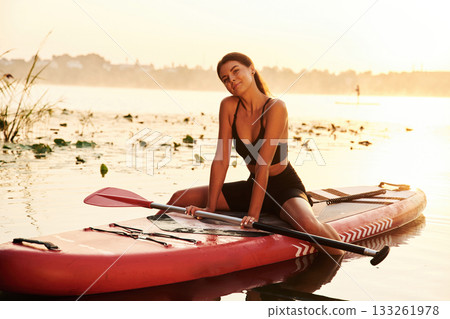 Positive, joyful facial expression. Young woman is with the sup board on the lake 133261978