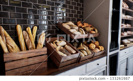 A cozy bakery offers a tempting variety of artisanal breads, artfully arranged in wooden crates. Freshly baked loaves and rolls invite customers to savor their warm aroma. A cozy bakery offers a tempting variety of artisanal breads, artfully arranged in wooden crates. Freshly baked loaves and rolls invite customers to savor their warm aroma. 133261987