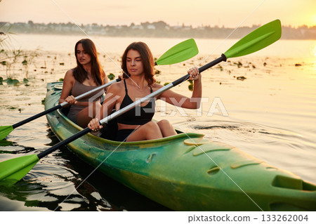 Rowing with oars. Women friends are on sup board on the lake together Rowing with oars. Women friends are on sup board on the lake together 133262004