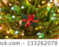 Christmas present on Christmas tree with garland lights , Gift in green box with red ribbon , New Year holidays present 133262078