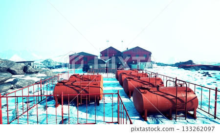 A remote research station contrasts strikingly with the icy terrain, showcasing vibrant red tanks nestled among rocks and snow. Flags flutter, hinting at exploration and discovery. 133262097