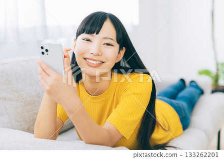 A woman lying on the sofa and using a smartphone 133262201