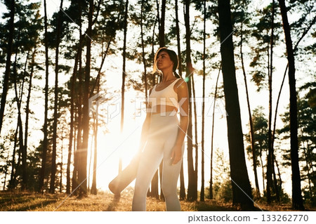 Bright sunlight, holding mat. Woman is doing yoga fitness exercises in the forest 133262770