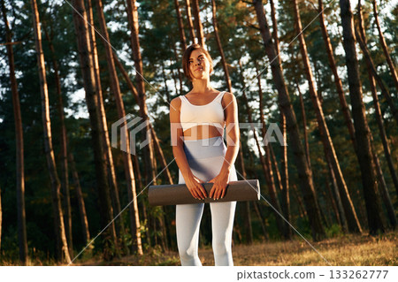 Ready for training, holding mat. Woman is doing yoga fitness exercises in the forest Ready for training, holding mat. Woman is doing yoga fitness exercises in the forest 133262777