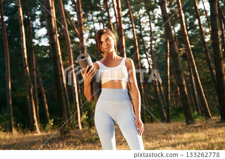 Ready for training, holding mat. Woman is doing yoga fitness exercises in the forest Ready for training, holding mat. Woman is doing yoga fitness exercises in the forest 133262778