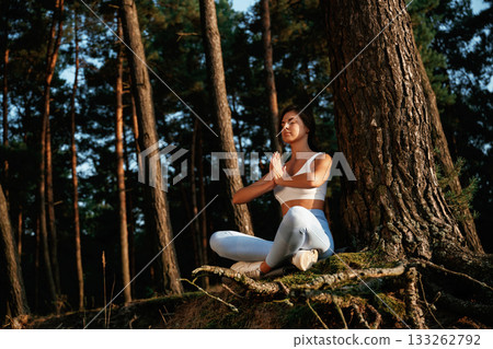On the roots of the tree. Woman is doing yoga fitness exercises in the forest 133262792