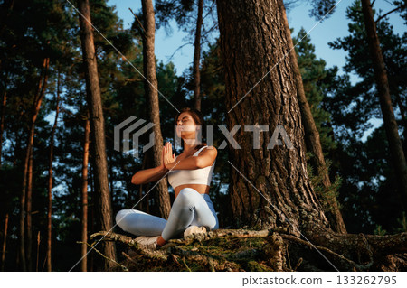 On the roots of the tree. Woman is doing yoga fitness exercises in the forest 133262795