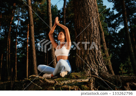 On the roots of the tree. Woman is doing yoga fitness exercises in the forest 133262796