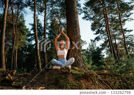Standard lotus pose. Woman is doing yoga fitness exercises in the forest 133262798