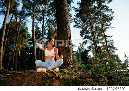 Standard lotus pose. Woman is doing yoga fitness exercises in the forest Standard lotus pose. Woman is doing yoga fitness exercises in the forest 133262801