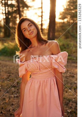Front view. Pretty young woman in pink dress is in the forest 133262829