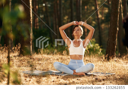 Sitting in lotus pose. Woman is doing yoga fitness exercises in the forest 133262855