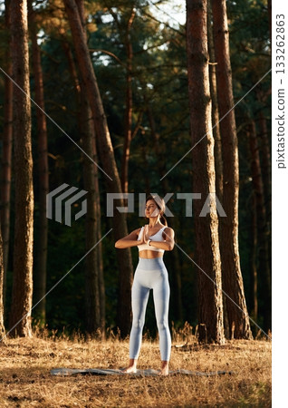 Wellbeing outdoors. Woman is doing yoga fitness exercises in the forest Wellbeing outdoors. Woman is doing yoga fitness exercises in the forest 133262863