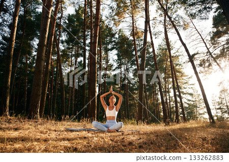 Meditation, calm mind. Woman is doing yoga fitness exercises in the forest Meditation, calm mind. Woman is doing yoga fitness exercises in the forest 133262883