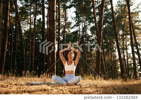 On the mat. Woman is doing yoga fitness exercises in the forest 133262884