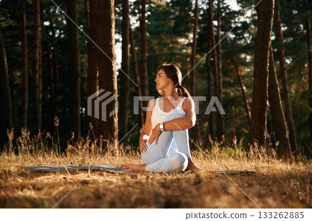 On the mat. Woman is doing yoga fitness exercises in the forest 133262885