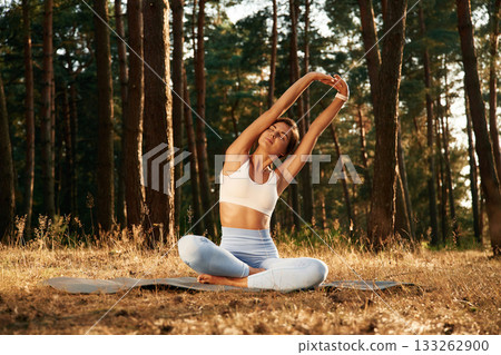 Hands are up, warm up. Woman is doing yoga fitness exercises in the forest Hands are up, warm up. Woman is doing yoga fitness exercises in the forest 133262900