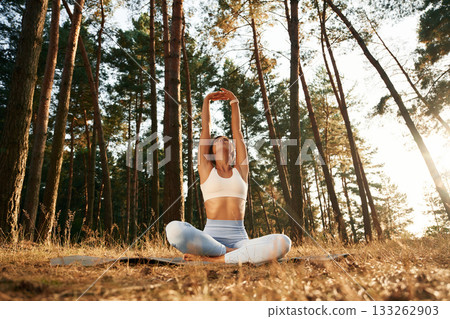 Hands are up, warm up. Woman is doing yoga fitness exercises in the forest 133262903