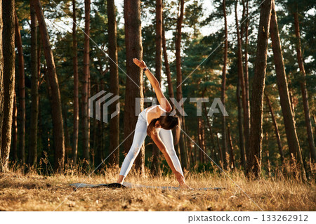 Windmill exercise. Woman is doing yoga fitness exercises in the forest Windmill exercise. Woman is doing yoga fitness exercises in the forest 133262912
