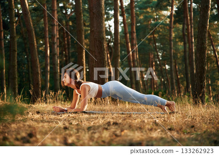 Woman is doing yoga fitness exercises in the forest Woman is doing yoga fitness exercises in the forest 133262923