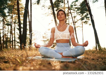 Peace and quiet, sitting. Woman is doing yoga fitness exercises in the forest 133262931