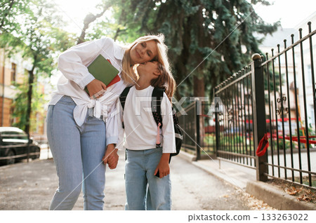 Smiling, positive emotions. Schoolgirl with her mother are outdoors together Smiling, positive emotions. Schoolgirl with her mother are outdoors together 133263022